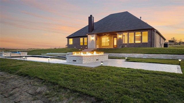 view of front of house featuring a patio area, a yard, and a fire pit