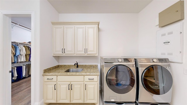 laundry room with cabinets, wood-type flooring, independent washer and dryer, and sink