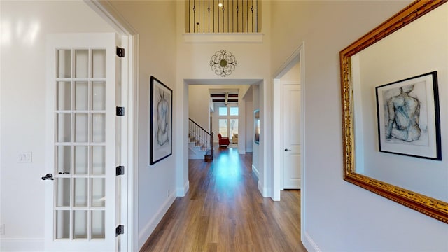 corridor featuring a towering ceiling and hardwood / wood-style flooring