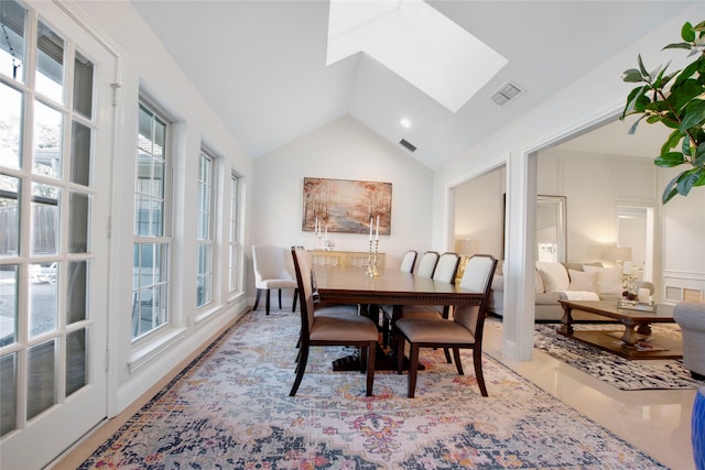 dining area with light tile patterned floors, lofted ceiling with skylight, and plenty of natural light