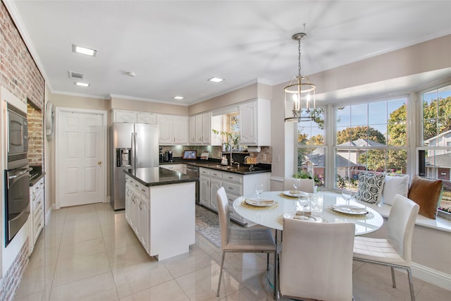 kitchen with backsplash, appliances with stainless steel finishes, decorative light fixtures, a kitchen island, and white cabinetry