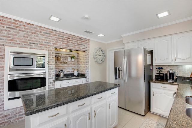 kitchen with white cabinetry, stainless steel appliances, brick wall, light tile patterned flooring, and ornamental molding