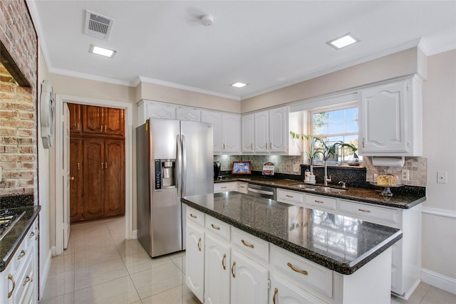 kitchen featuring white cabinets, appliances with stainless steel finishes, a center island, and backsplash