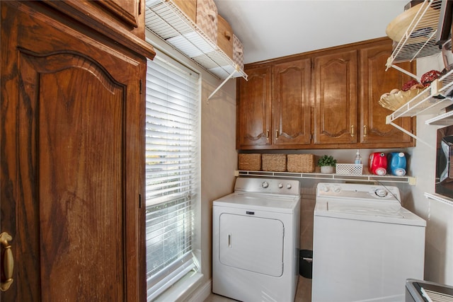 laundry room featuring washing machine and clothes dryer and cabinets