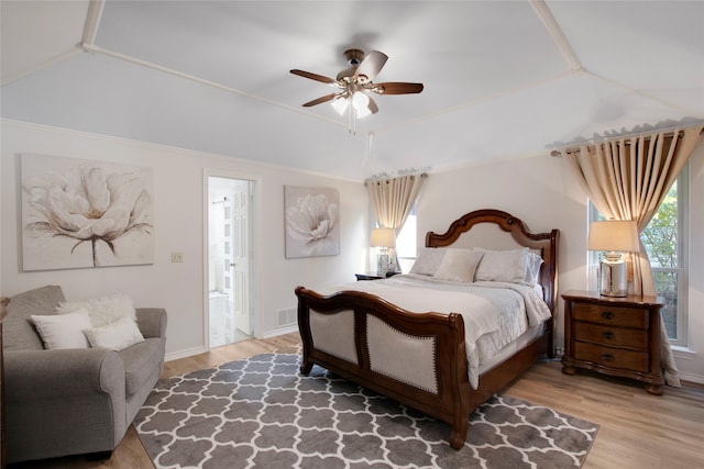 bedroom with ensuite bath, ceiling fan, wood-type flooring, and lofted ceiling