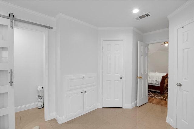 interior space featuring a barn door, light hardwood / wood-style flooring, and ornamental molding