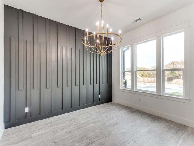 unfurnished dining area featuring a chandelier and light wood-type flooring