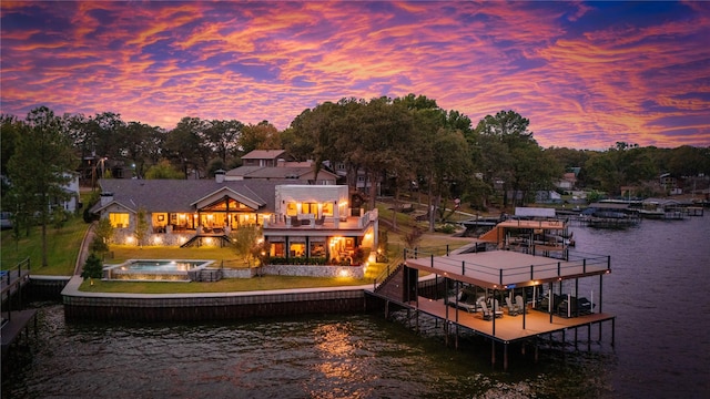 back house at dusk featuring a balcony and a water view