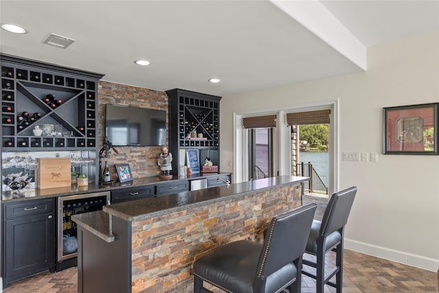 bar featuring parquet flooring, wine cooler, and dark stone countertops