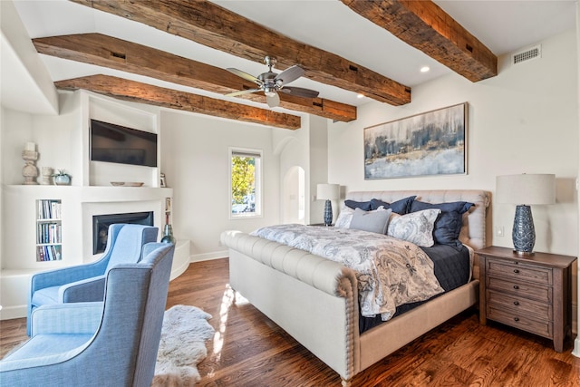 bedroom featuring ceiling fan, dark hardwood / wood-style flooring, and beamed ceiling