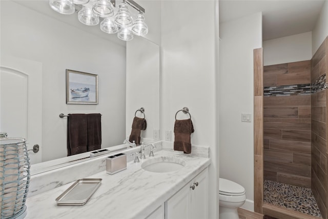 bathroom featuring tiled shower, vanity, and toilet