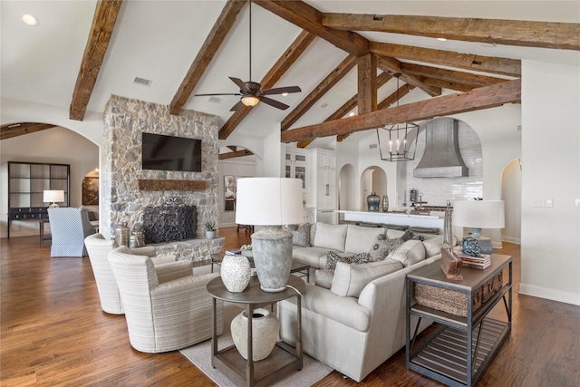 living room featuring beamed ceiling, dark hardwood / wood-style flooring, high vaulted ceiling, and a stone fireplace