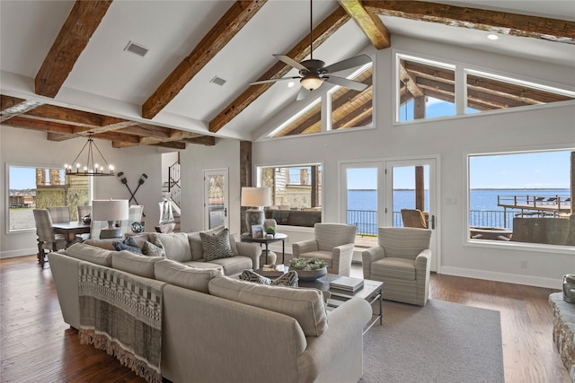 living room with ceiling fan with notable chandelier, dark wood-type flooring, beam ceiling, a water view, and high vaulted ceiling