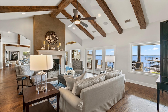 living room with dark hardwood / wood-style flooring, a fireplace, a water view, high vaulted ceiling, and beamed ceiling