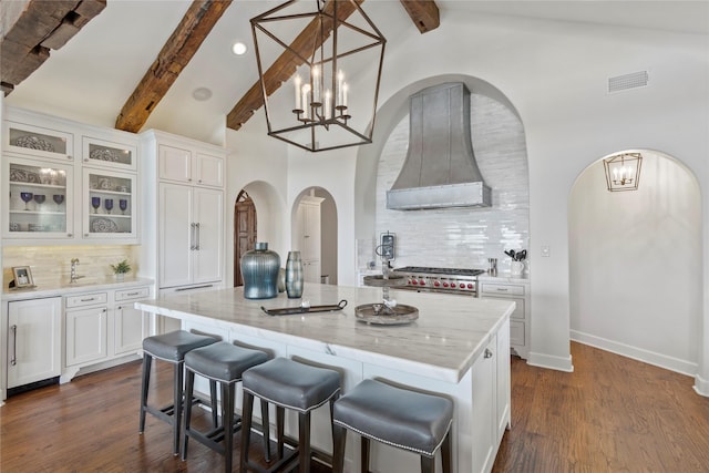 kitchen with custom exhaust hood, a center island, white cabinetry, and backsplash