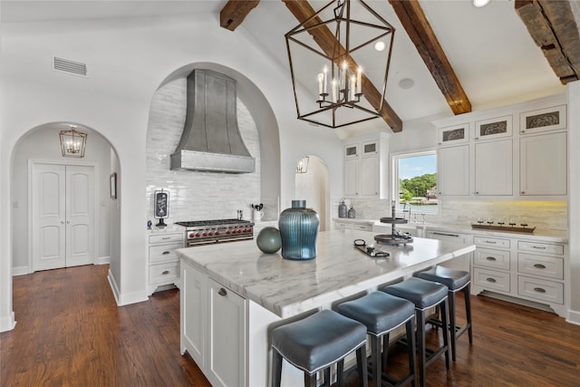 kitchen with beam ceiling, white cabinetry, a center island, dark hardwood / wood-style floors, and backsplash