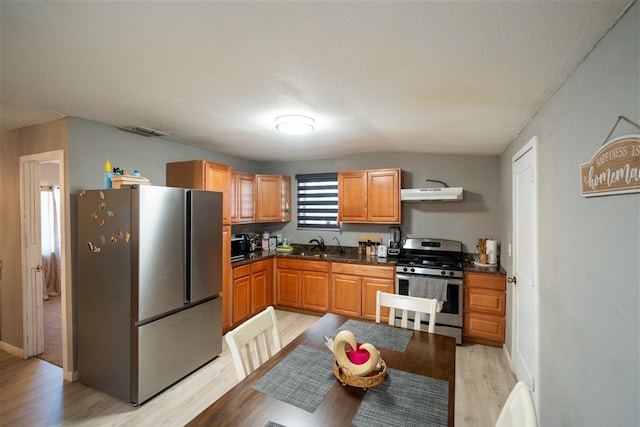 kitchen featuring sink, light hardwood / wood-style floors, a textured ceiling, exhaust hood, and appliances with stainless steel finishes