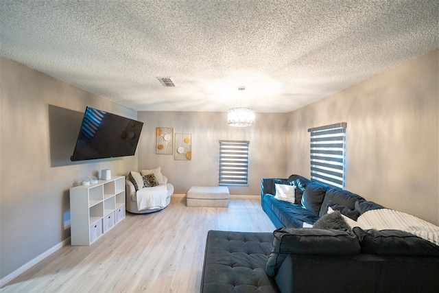 living room featuring an inviting chandelier, a textured ceiling, and light wood-type flooring