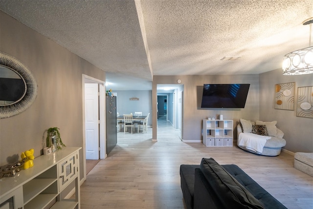 living room with wood-type flooring, a textured ceiling, and a notable chandelier