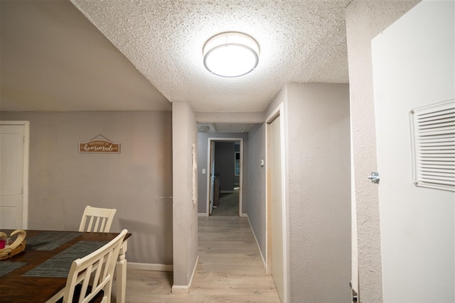 hall featuring light hardwood / wood-style floors and a textured ceiling