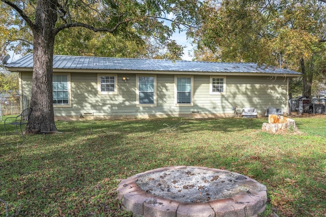 rear view of property featuring a yard and an outdoor fire pit