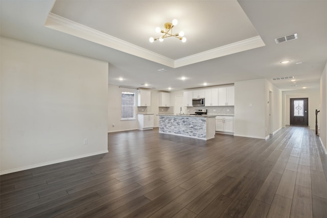 unfurnished living room featuring a raised ceiling, ornamental molding, an inviting chandelier, and dark hardwood / wood-style flooring