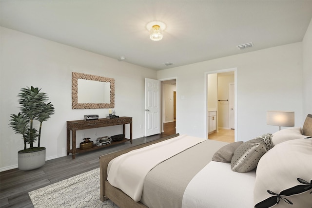 bedroom with dark wood-type flooring and connected bathroom