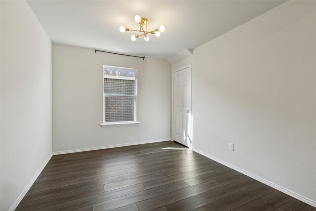 spare room with dark wood-type flooring and a chandelier