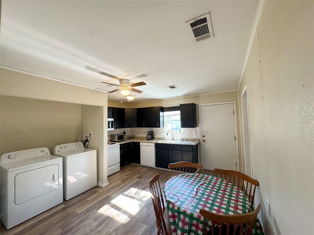 kitchen with white appliances, sink, hardwood / wood-style flooring, washer and dryer, and ceiling fan