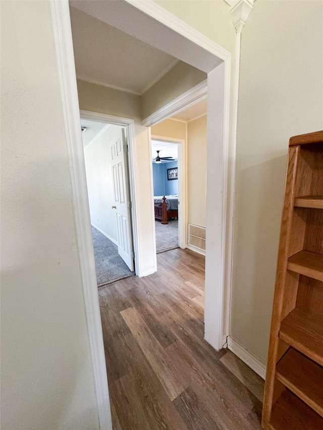 hall with wood-type flooring and ornamental molding