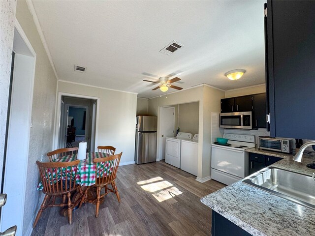 kitchen featuring appliances with stainless steel finishes, ceiling fan, dark wood-type flooring, sink, and washing machine and dryer