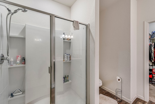 bathroom with a shower with shower door, toilet, and hardwood / wood-style flooring