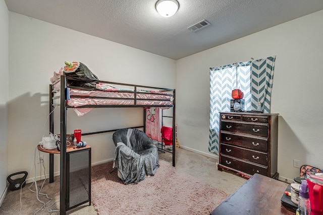 bedroom with light colored carpet and a textured ceiling