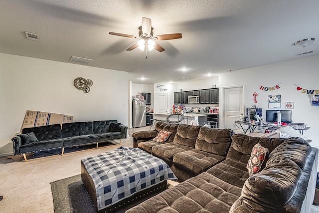 carpeted living room featuring ceiling fan and a textured ceiling