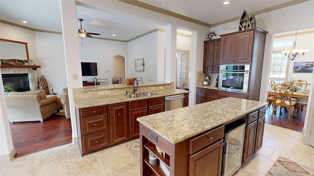 kitchen with a stone fireplace, sink, a center island, appliances with stainless steel finishes, and beverage cooler