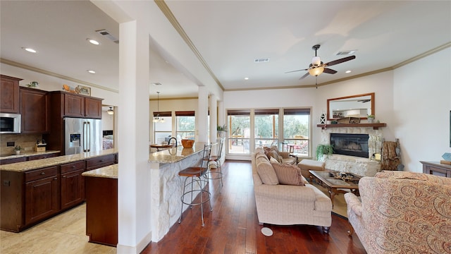 kitchen featuring light stone countertops, a kitchen breakfast bar, light wood-type flooring, stainless steel appliances, and a fireplace