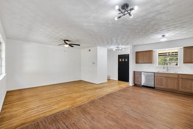 kitchen featuring dishwasher, ceiling fan with notable chandelier, sink, light wood-type flooring, and a textured ceiling