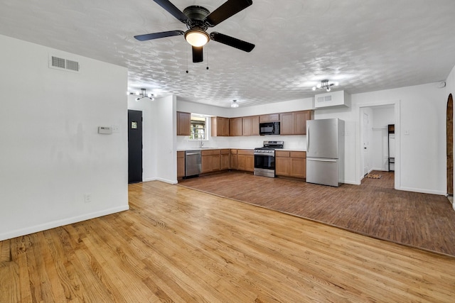 kitchen with ceiling fan, light hardwood / wood-style flooring, stainless steel appliances, and a textured ceiling