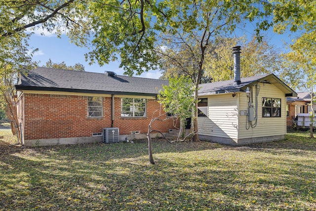 rear view of property featuring central air condition unit and a yard