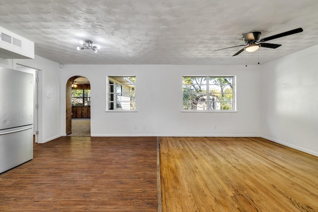 spare room featuring a textured ceiling, light hardwood / wood-style floors, and ceiling fan with notable chandelier