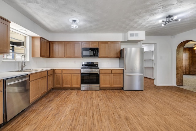 kitchen featuring sink, light hardwood / wood-style floors, a textured ceiling, and appliances with stainless steel finishes