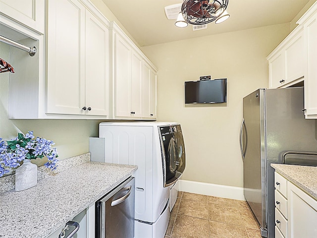 washroom with washing machine and clothes dryer, light tile patterned floors, and cabinets