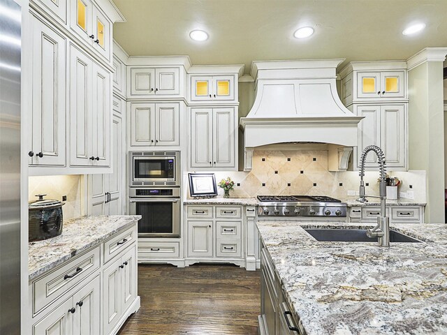 kitchen featuring appliances with stainless steel finishes, light stone counters, dark wood-type flooring, and sink