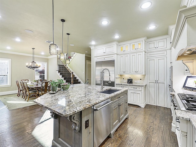 kitchen featuring appliances with stainless steel finishes, sink, a large island with sink, dark hardwood / wood-style floors, and hanging light fixtures