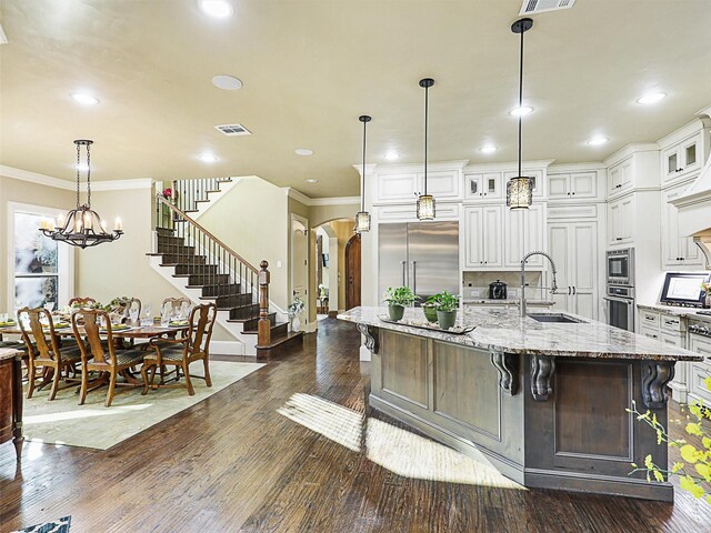 kitchen with light stone counters, white cabinetry, stainless steel appliances, and dark wood-type flooring