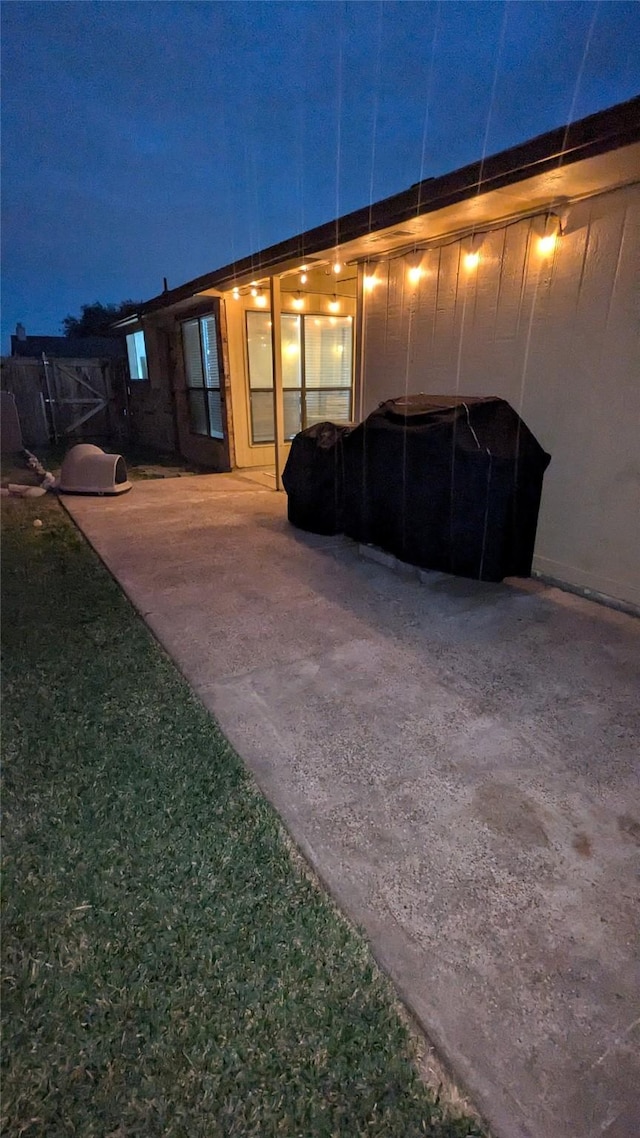 back house at night featuring a patio