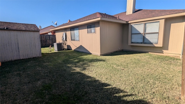 back of property with a lawn, central AC unit, and a storage unit