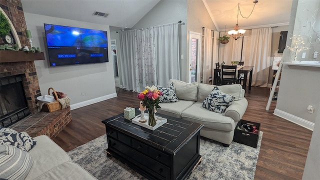 living room with lofted ceiling, dark hardwood / wood-style floors, a notable chandelier, and a brick fireplace