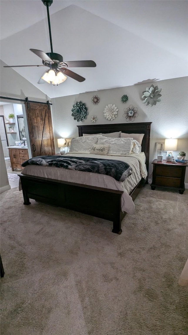 bedroom featuring lofted ceiling, ensuite bath, carpet flooring, ceiling fan, and a barn door