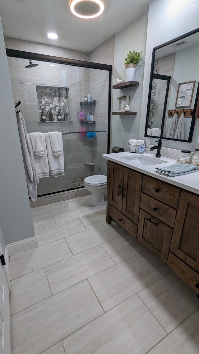 bathroom with vanity, toilet, and a shower with shower door